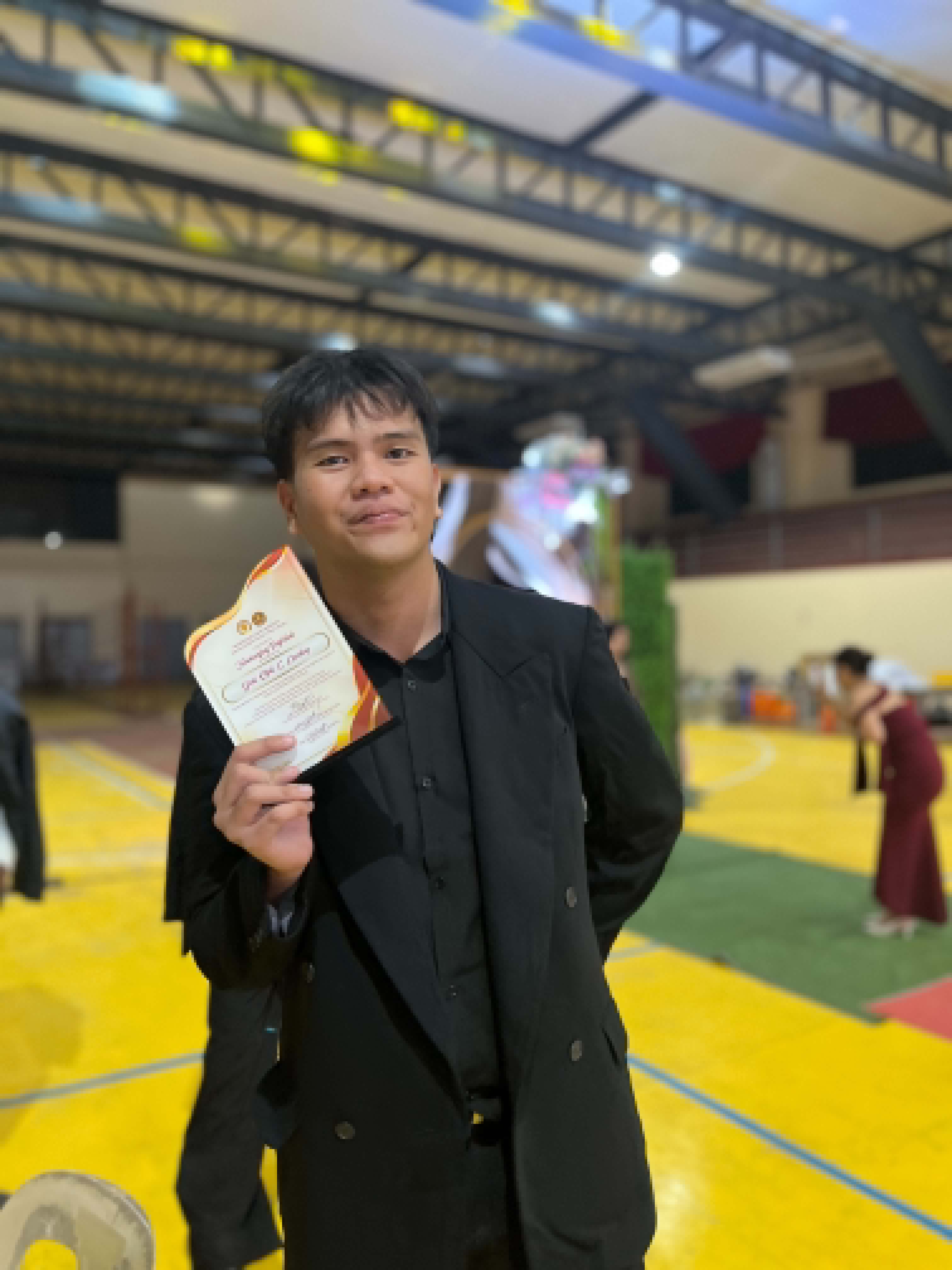 Gene holding an award certificate at a university event